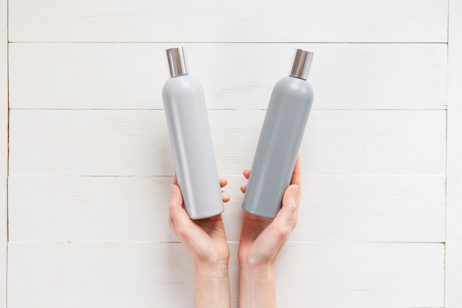 The woman chooses one of the two shampoos in the bottle. The concept of beauty and choice of cosmetics. Top view woman hands with bottles